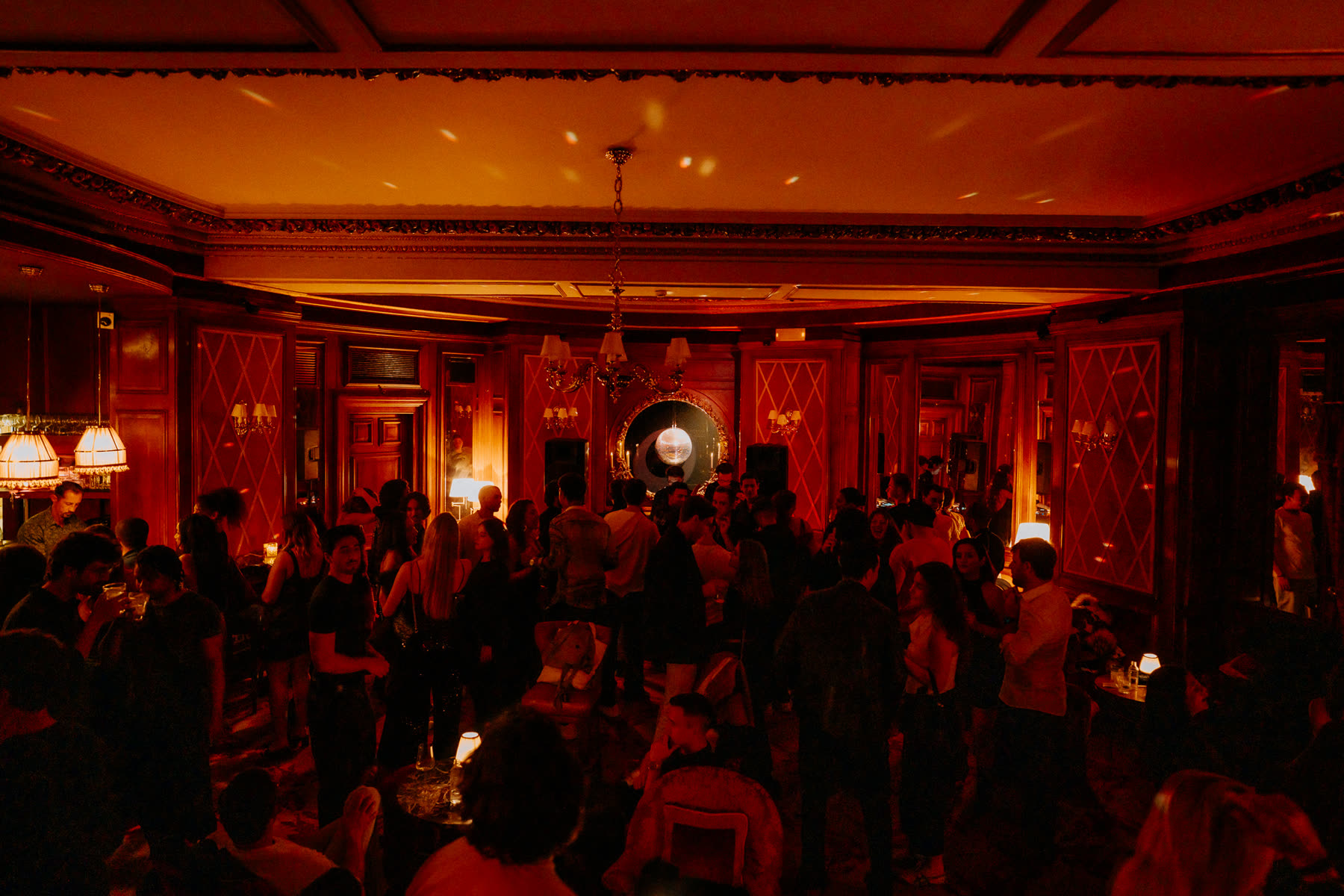 Panelled ballroom full of dancers under a chandelier